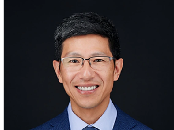 Man with glasses wearing a blue suit and blue tie