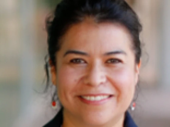 Woman wearing a green and white shirt with orange earrings